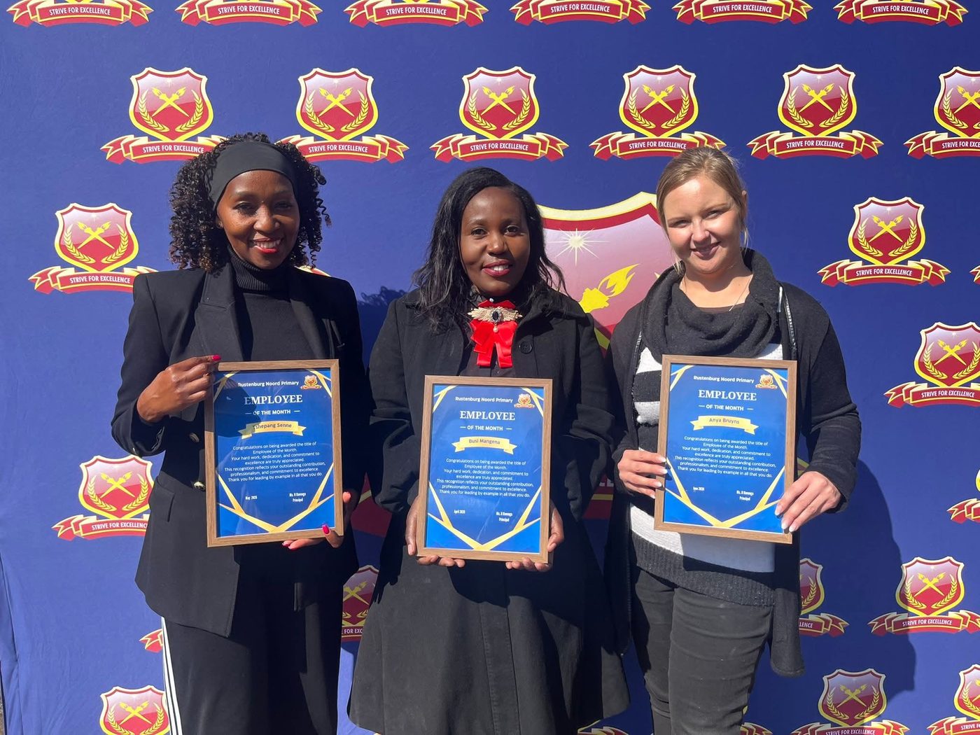 Three educators proudly holding their framed Employee of the Month certificates