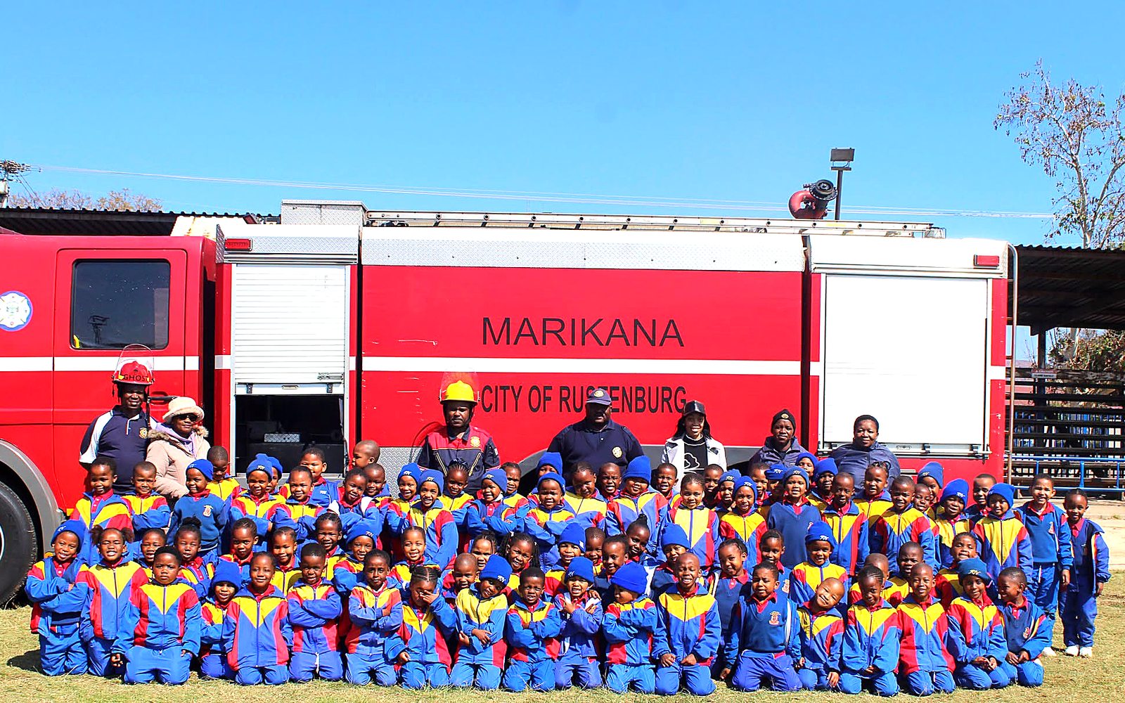 Grade R Nories posing with firefighters in front of a City of Rustenburg fire engine