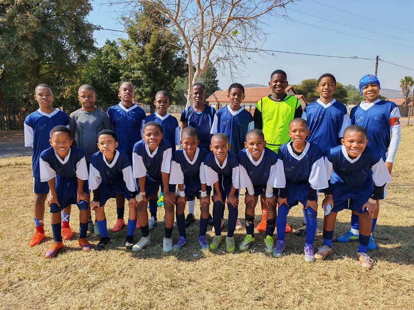 The boys' soccer team posing in their blue kit on the school field