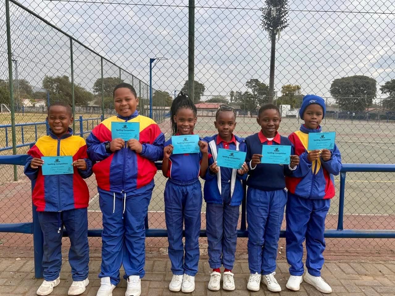 Six proud learners holding their spelling competition certificates