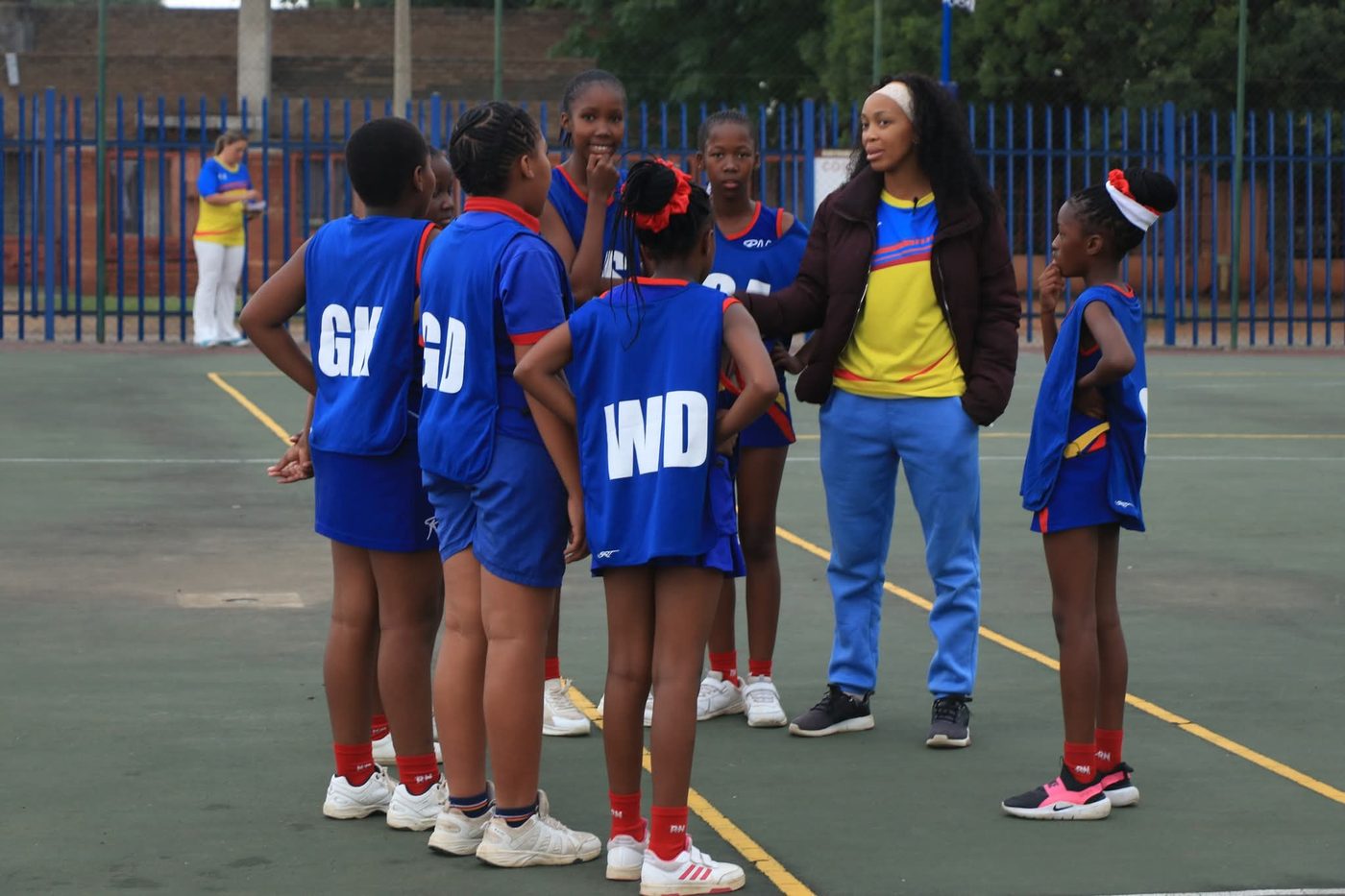 A Noord Primary netball coach talking tactics with her team courtside